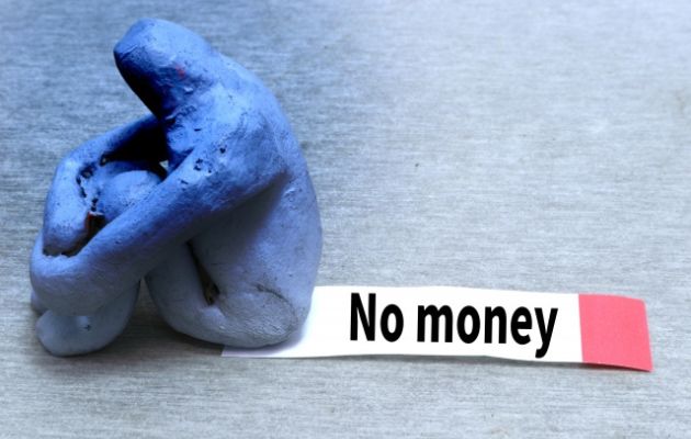 膝を抱えて座っている人形が付箋を踏んでいて、付箋には「No money」と書かれている写真