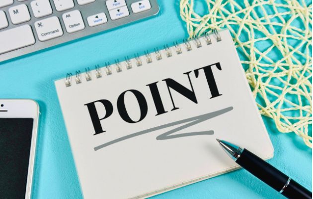 ノートに「POINT」と書かれており、周りにキーボードとスマートフォン、ボールペンが置いてある写真