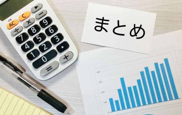 電卓、ボールペン、棒グラフが置いてある机に「まとめ」と書いてある写真