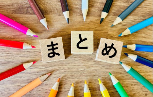 積み木に「まとめ」と書かれており、回りに色鉛筆が円状に並んでいる写真