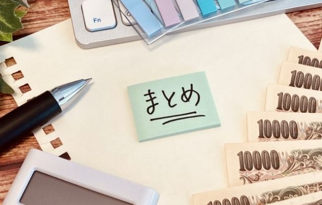 ノートを1枚破った紙の上に付箋で「まとめ」と書かれている。周りには1万円の現金と電卓、ボールペン、キーボードや付箋が置いてある写真