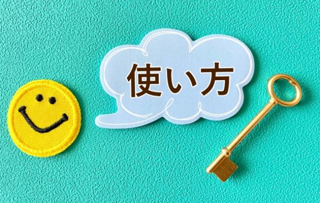 ニコちゃんマークのアップリケから吹き出しで「使い方」と言葉がでている。吹き出しの横に金色に鍵が置いてある写真