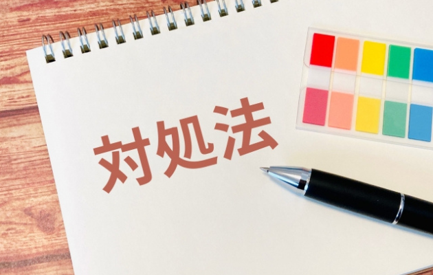 ノートに「対処法」と書かれており、周りにカラフルな付箋とボールペンが置いてある写真