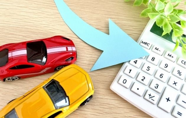 おもちゃの車と電卓の間に上から下へ下げるような矢印が書かれている写真