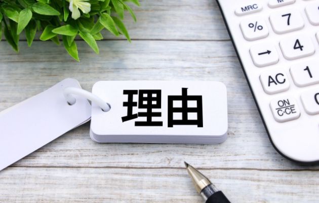 暗記カードに「理由」と書かれており、周りにボールペンと電卓が置いてある写真