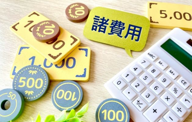 電卓から「諸費用」と吹き出しが出ている。その周りにおもちゃの現金が散りばめられている写真