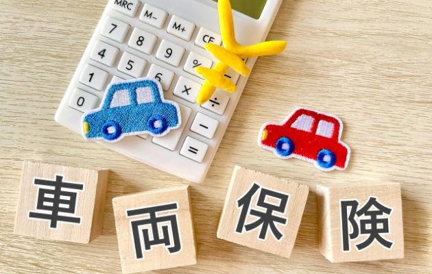 積み木に「車両保険」と書かれており、電卓と車と「￥」マークのアップリケが一緒に写っている写真